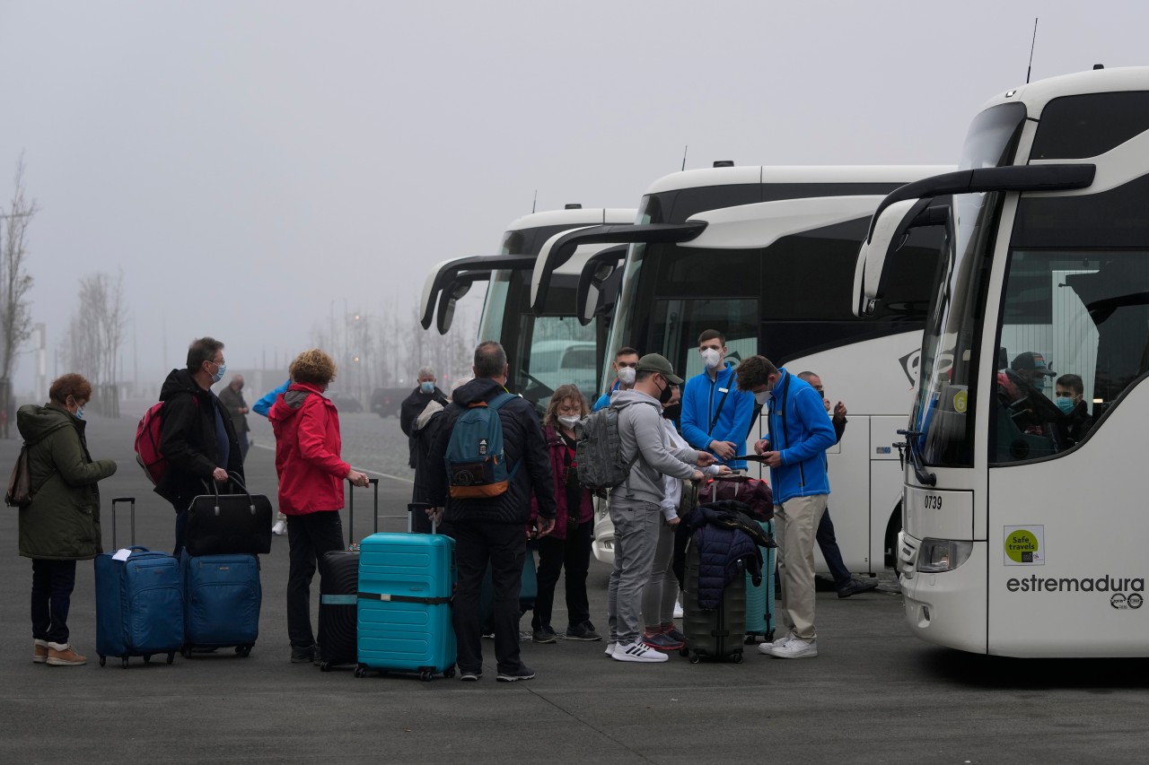 Passagiere stehen mit ihrem Gepäck vor einem Bus Schlange, um zum Flughafen von Lissabon gebracht zu werden, nachdem sie das Kreuzfahrtschiff „Aida Nova“ verlassen haben.