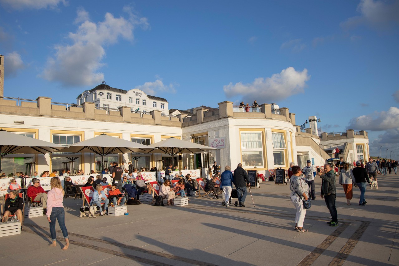 Touristen sitzen an der Promenade auf der Nordsee-Insel Borkum.