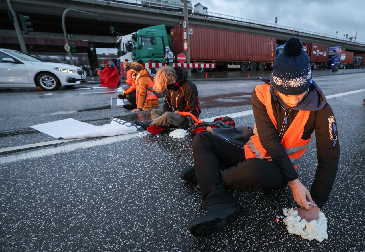 Klimaaktivisten der Aktion „Aufstand der letzten Generation“ blockieren am Morgen eine Kreuzung am Zollamt Waltershof zur Köhlbrandbrücke und zur Autobahn A7.