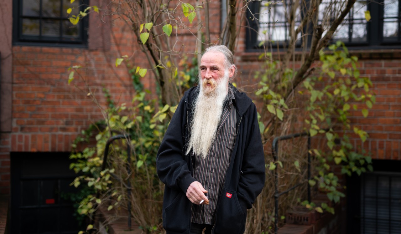 Der Obdachlose Volker Mähl steht im Hinterhof eines Hotels in Hamburg-Altona und raucht eine Zigarette.