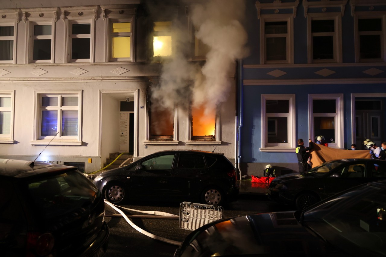 Flammen schlagen aus den Fenstern eines Mehrfamilienhauses. 
