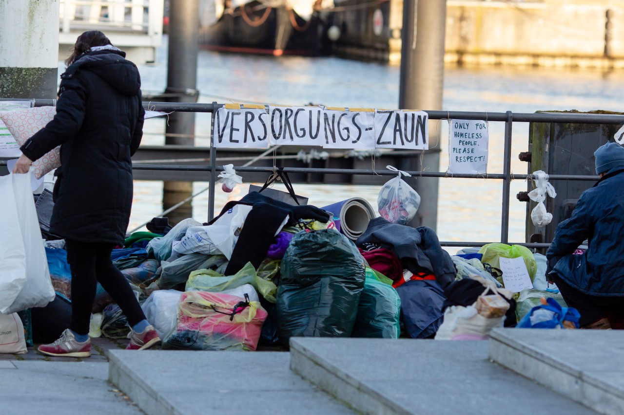 Säcke mit Kleidung liegen vor einem Geländer am Kieler Hafen.