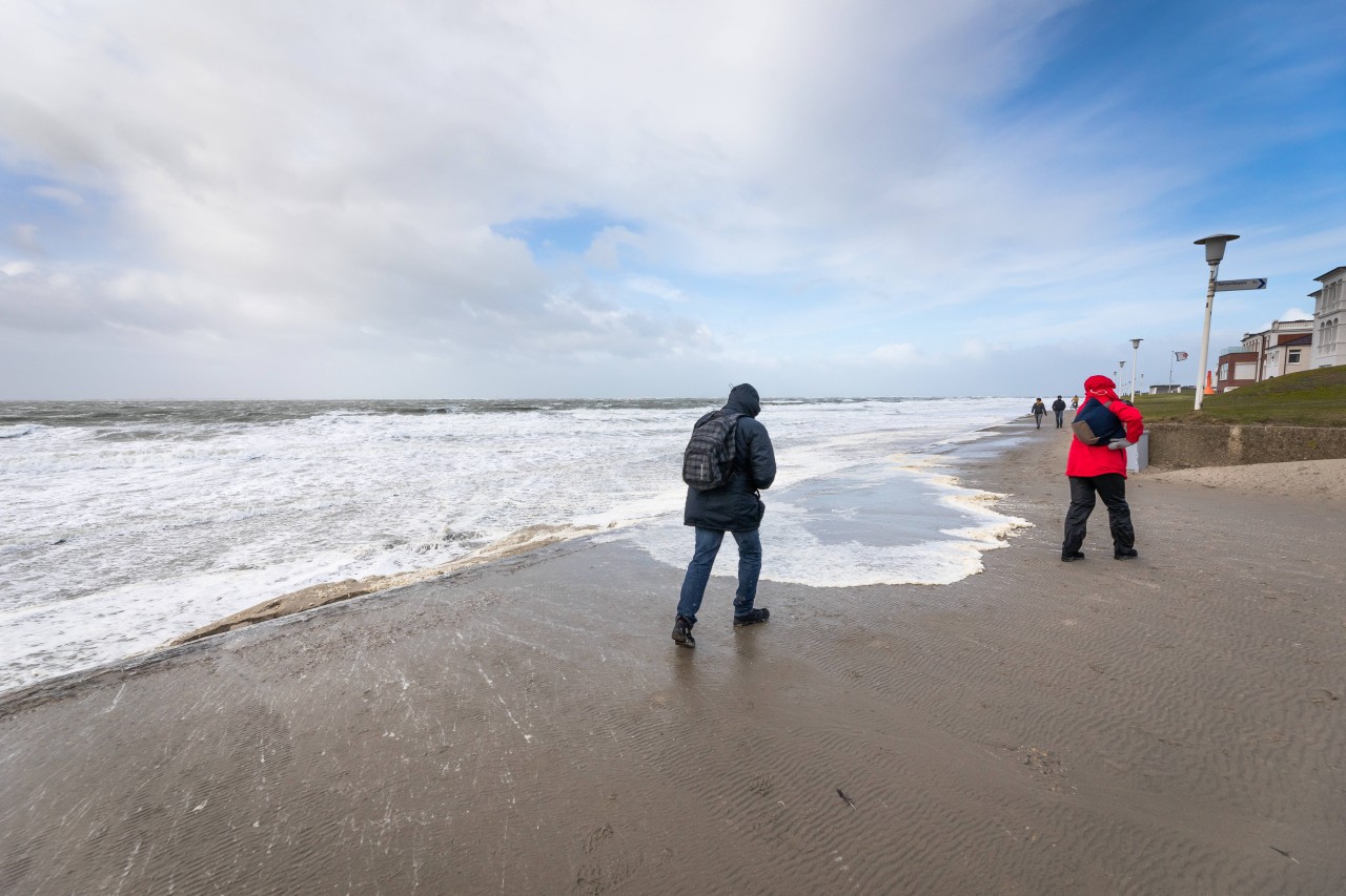 Menschen spazieren am Weststrand von Norderney am Meer.