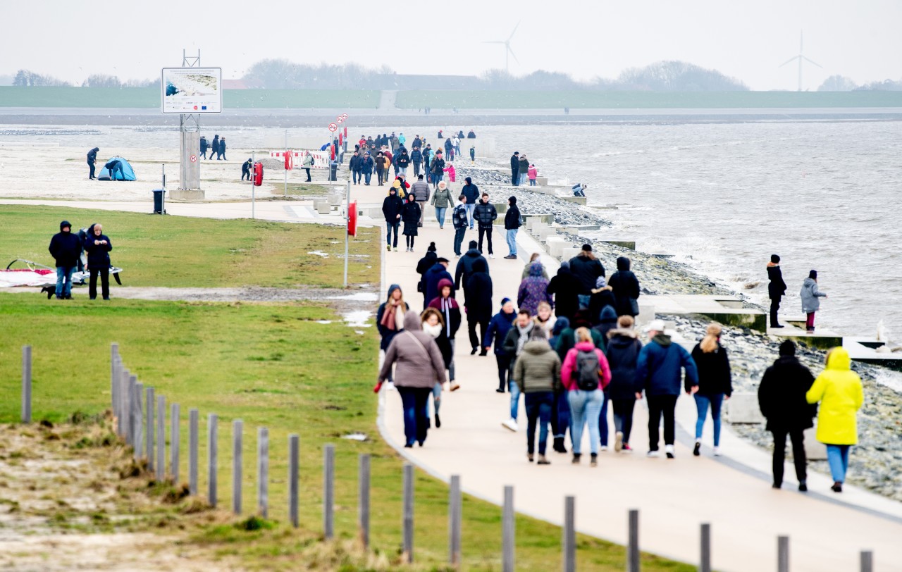 Zahlreiche Spaziergänger sind bei trübem Wetter auf der Promenade am Nordsee-Strand unterwegs.
