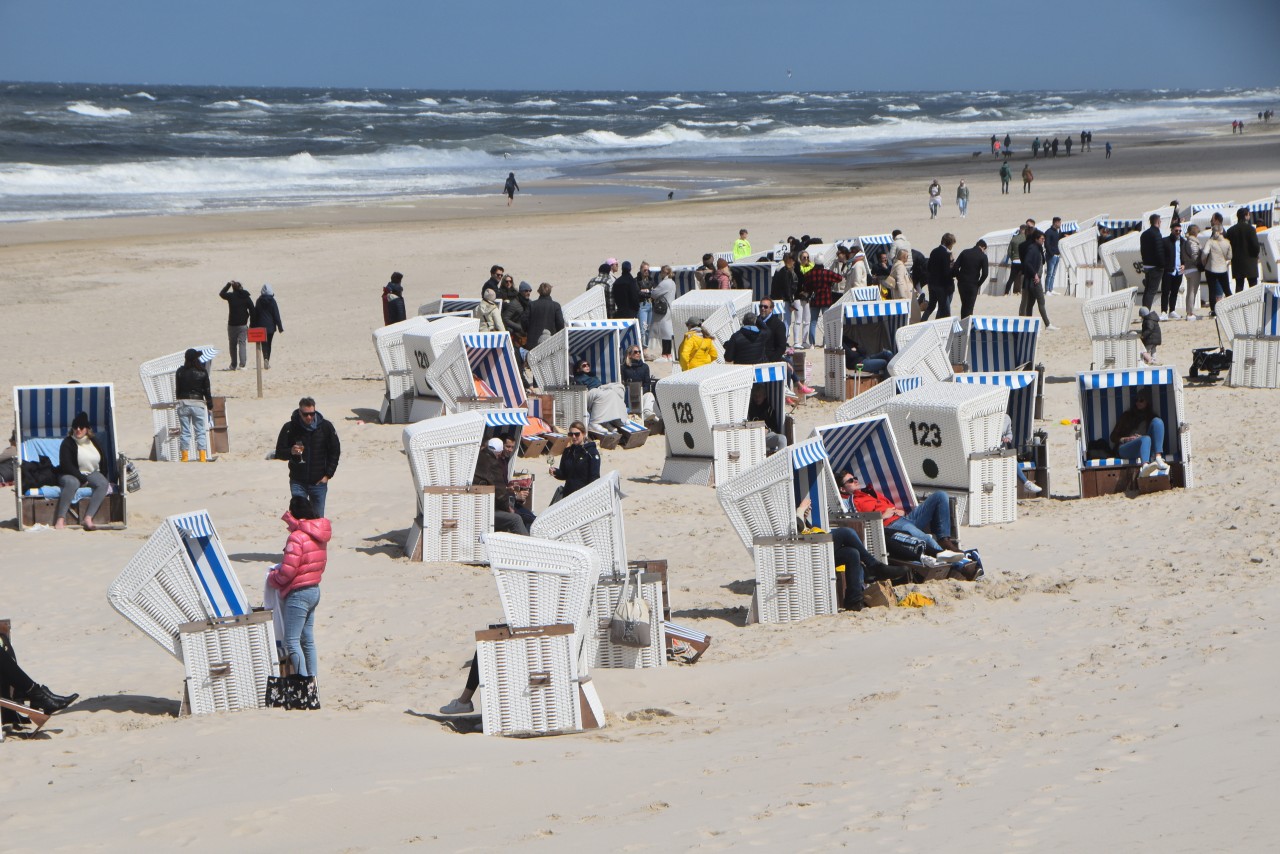 Menschen sitzen und stehen im Frühling an Strandkörben auf Sylt.