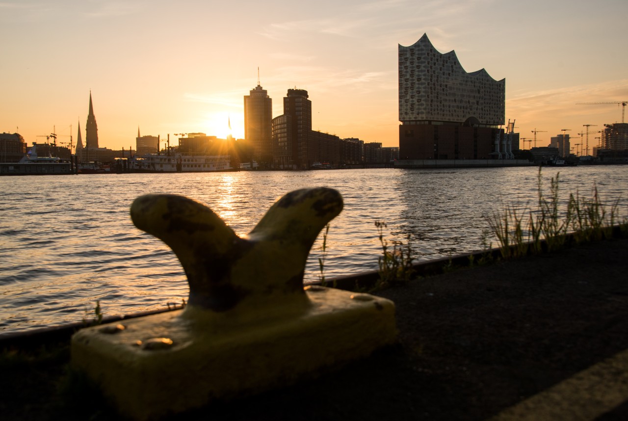 Die Sonne geht am Morgen im Hafen Hamburg an der Elbe mit der Elbphilharmonie auf.