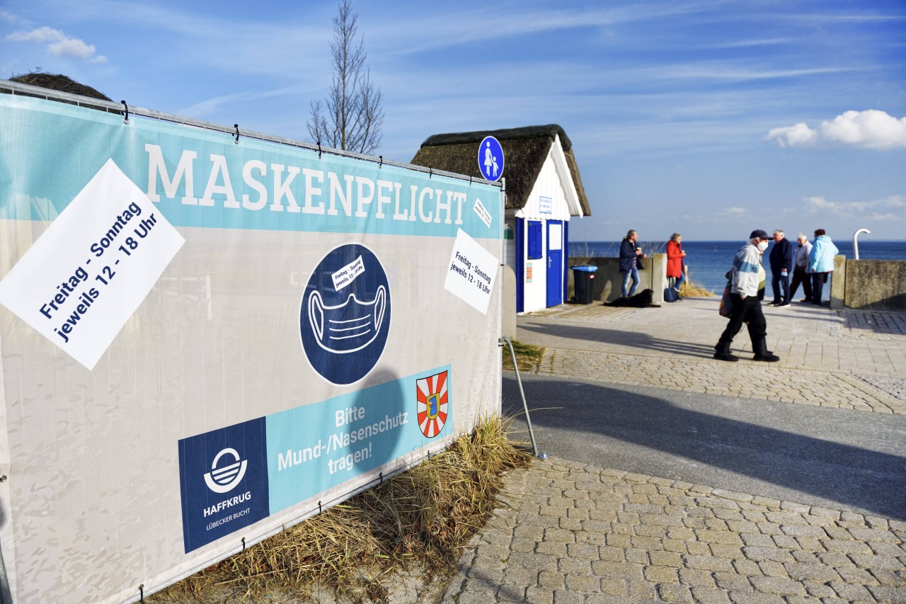 Ein Schild an der Promenade von Haffkrug an der Ostsee weist auf die Maskenpflicht hin. 