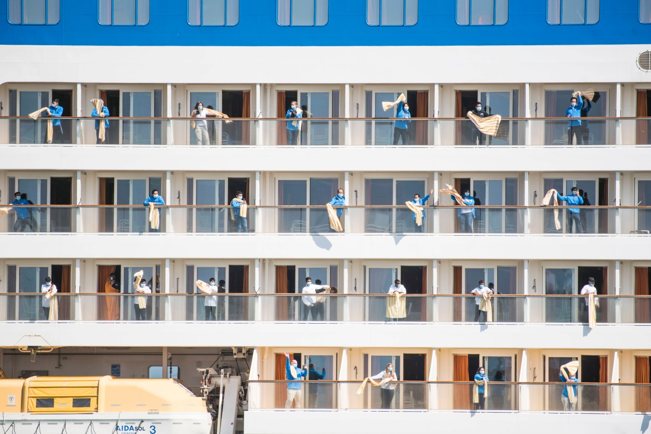 Die Besatzung der „Aida Sol“ winkt beim Einlaufen in das Seebad Rostock-Warnemünde mit Tüchern.