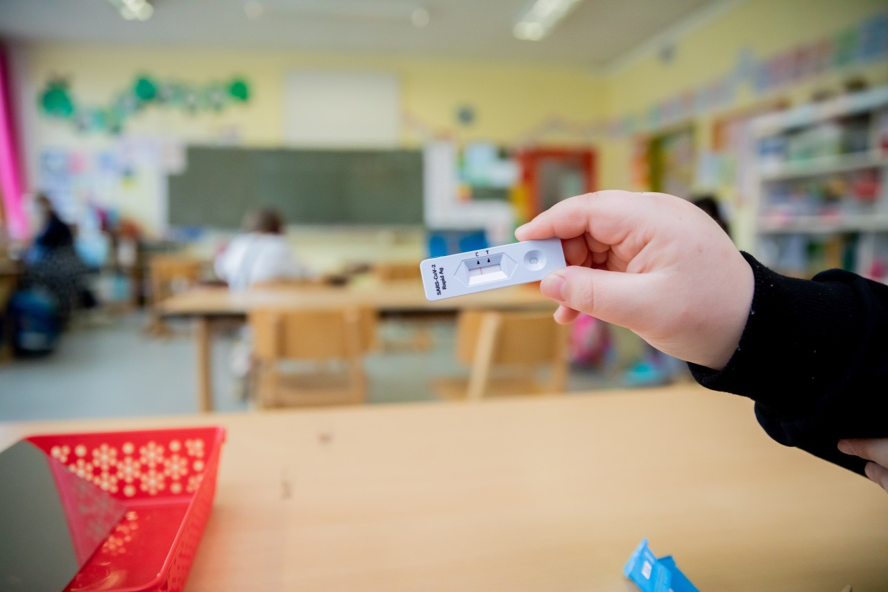 Ein Schüler hält bei einem Probelauf mit Corona-Schnelltests hoch.