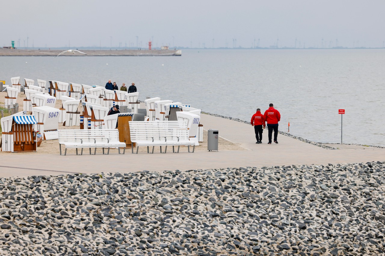 Ferien: Mitarbeiter des Strandservice gehen die Promenade in Büsum entlang.