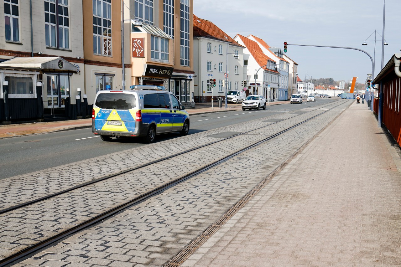 Flensburg: Ein Polizeifahrzeug fährt auf einer Straße am Hafen. Für zunächst eine Woche gelten verschärfte Corona-Maßnahmen in der Stadt.
