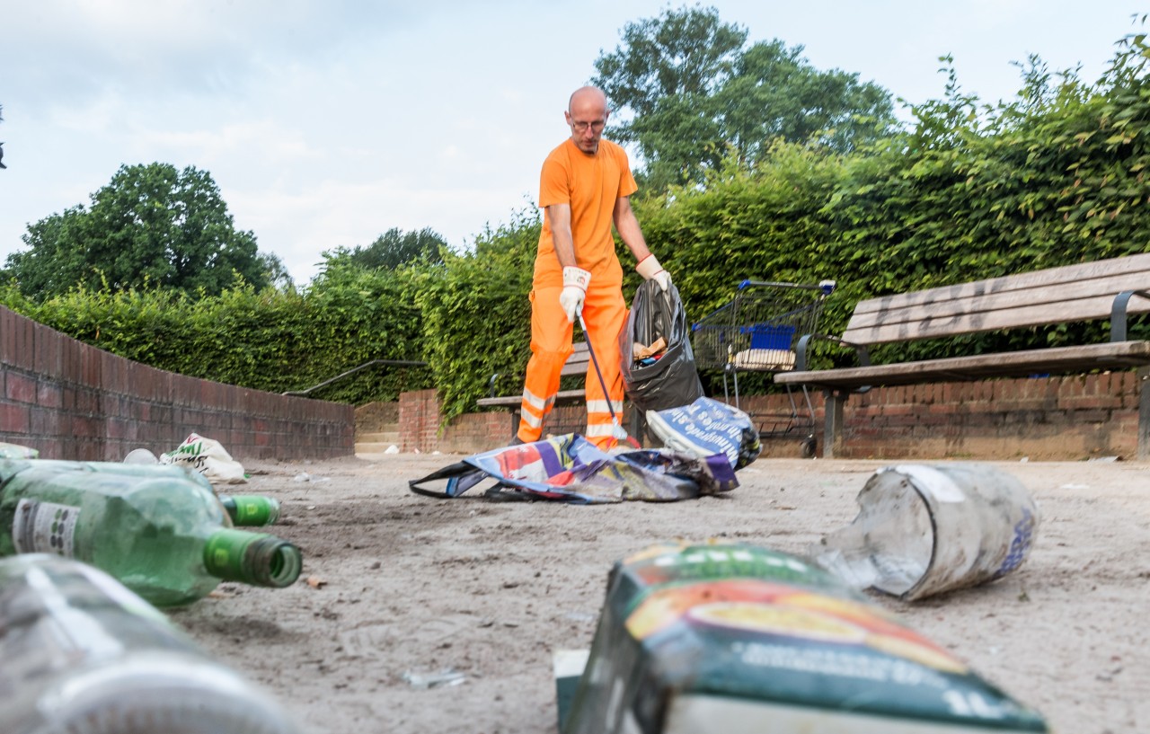 Ein Mitarbeiter der Stadtreinigung entfernt am frühen Morgen den Müll im Stadtpark, der dort nach einer lauen Sommernacht zurückgelassen wurde. 