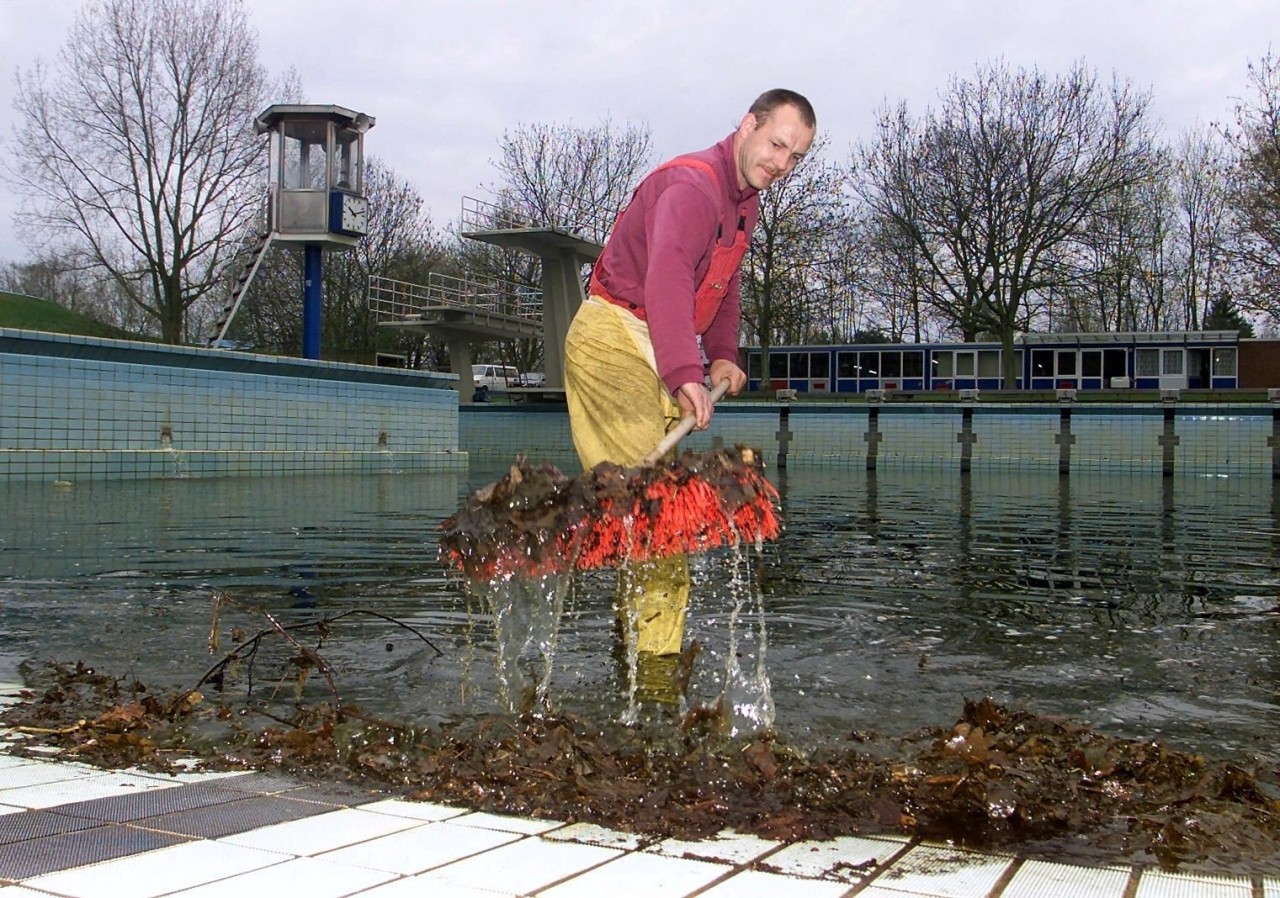 Frühjahr 2001, schon eine Weile her: Ein Mitarbeiter einer Reinigungsfirma fegt im Aschbergbad das Laub aus dem Schwimmbecken. 