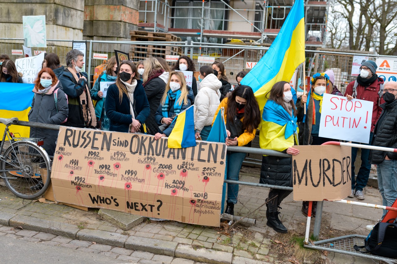 Teilnehmer einer Protestaktion gegen den russischen Einmarsch in die Ukraine stehen mit Schildern mit der Aufschrift "Russen sind Okkupanten!", "Murder" und "Stop Putin" vor dem Russischen Generalkonsulat.