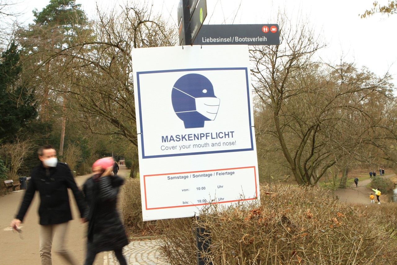 Ein Schild im Hamburger Stadtpark weist darauf hin, dass am Wochenende und an Feiertagen von 10 bis 18 Uhr Maskenpflicht besteht.