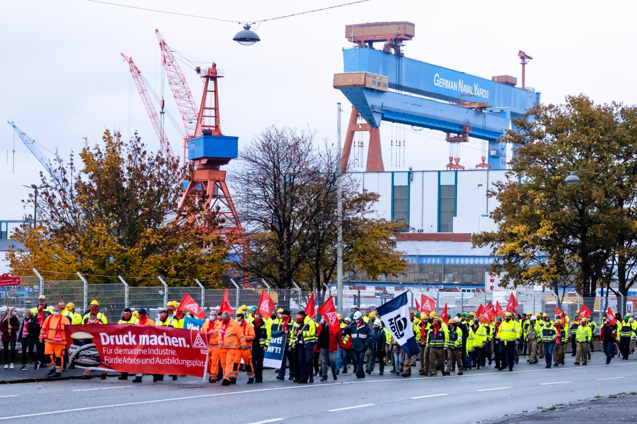 Teilnehmer einer Demonstration gehen auf einer Straße vor der Kieler Werft German Naval Yards.