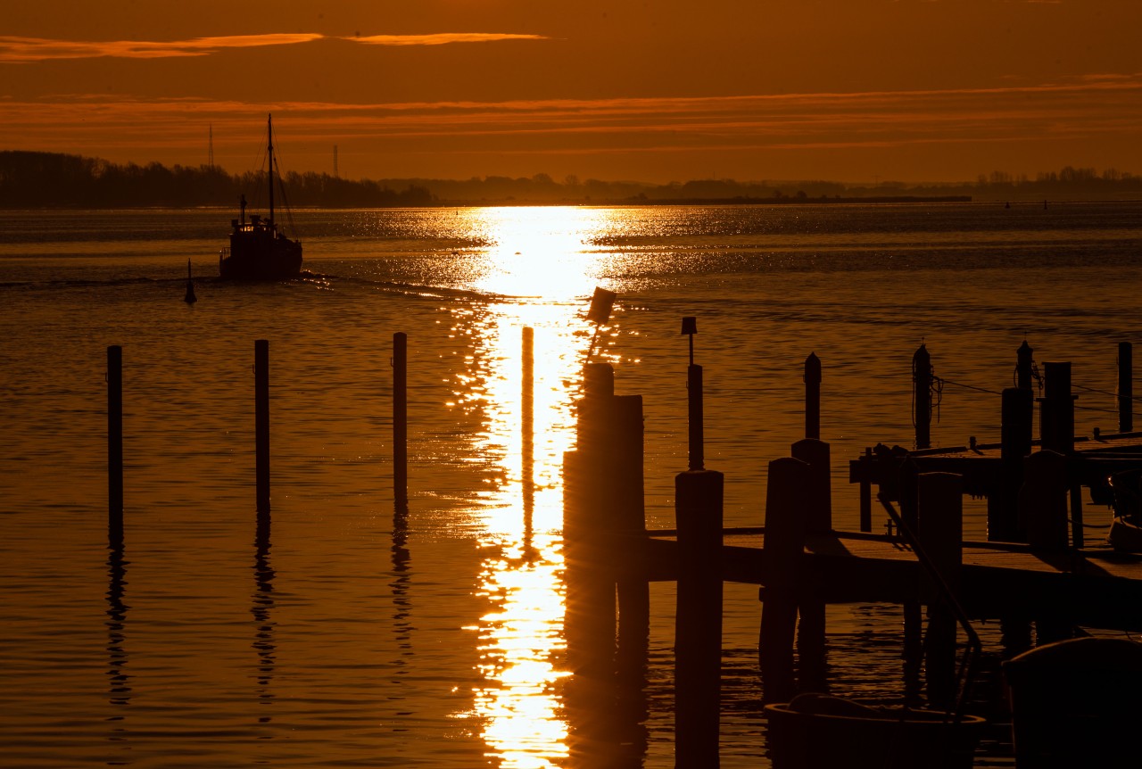 Ein Kutter fährt kurz nach Sonnenaufgang vom Hafen auf der Ostseeinsel Hiddensee auf die Ostsee. 