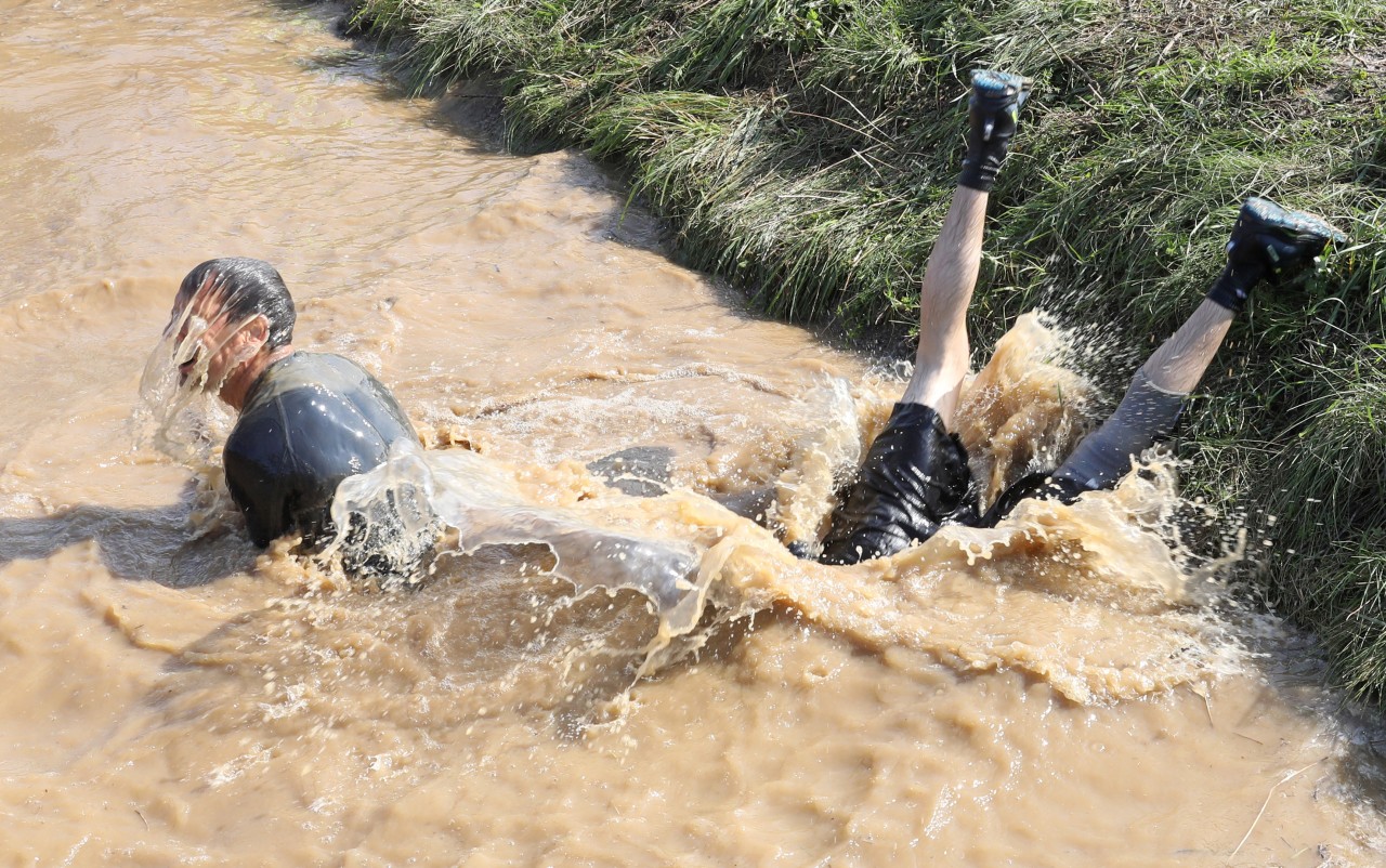 Beim Geländelauf „Mudder Island“ müssen Teilnehmer ein Wasserloch durchqueren. Das gelingt mal besser – und mal schlechter. 