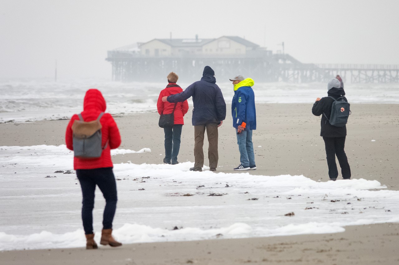 Spaziergänger sind bei stürmischem Wetter am Strand von St. Peter Ording unterwegs.