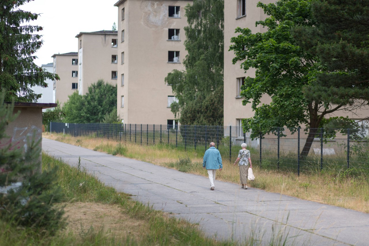 Rügen: Zwei Personen gehen am letzten unsanierten Teil des Prora-Baus an Block 5 entlang.