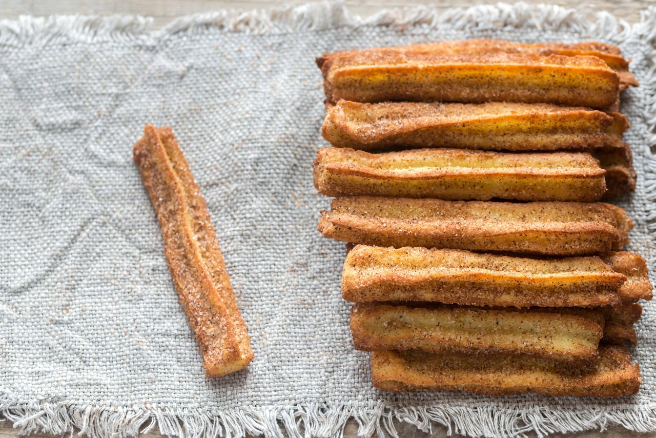 Churros sind ein spanisches Fettgebäck, das aus einer Mehl-Wasser-Mischung zubereitet, in heißem Öl frittiert und mit Zucker bestreut wird. 