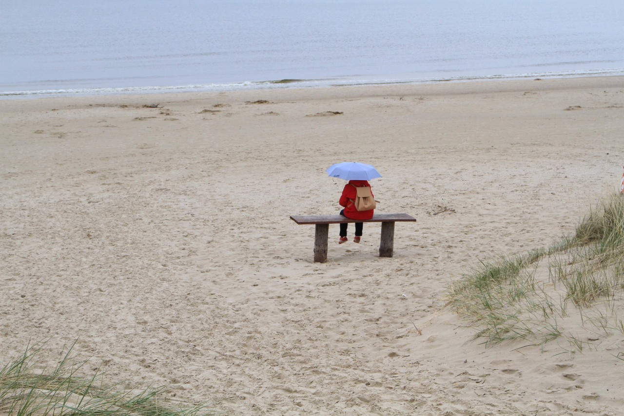 Eine Frau sitzt am Strand von Usedom.