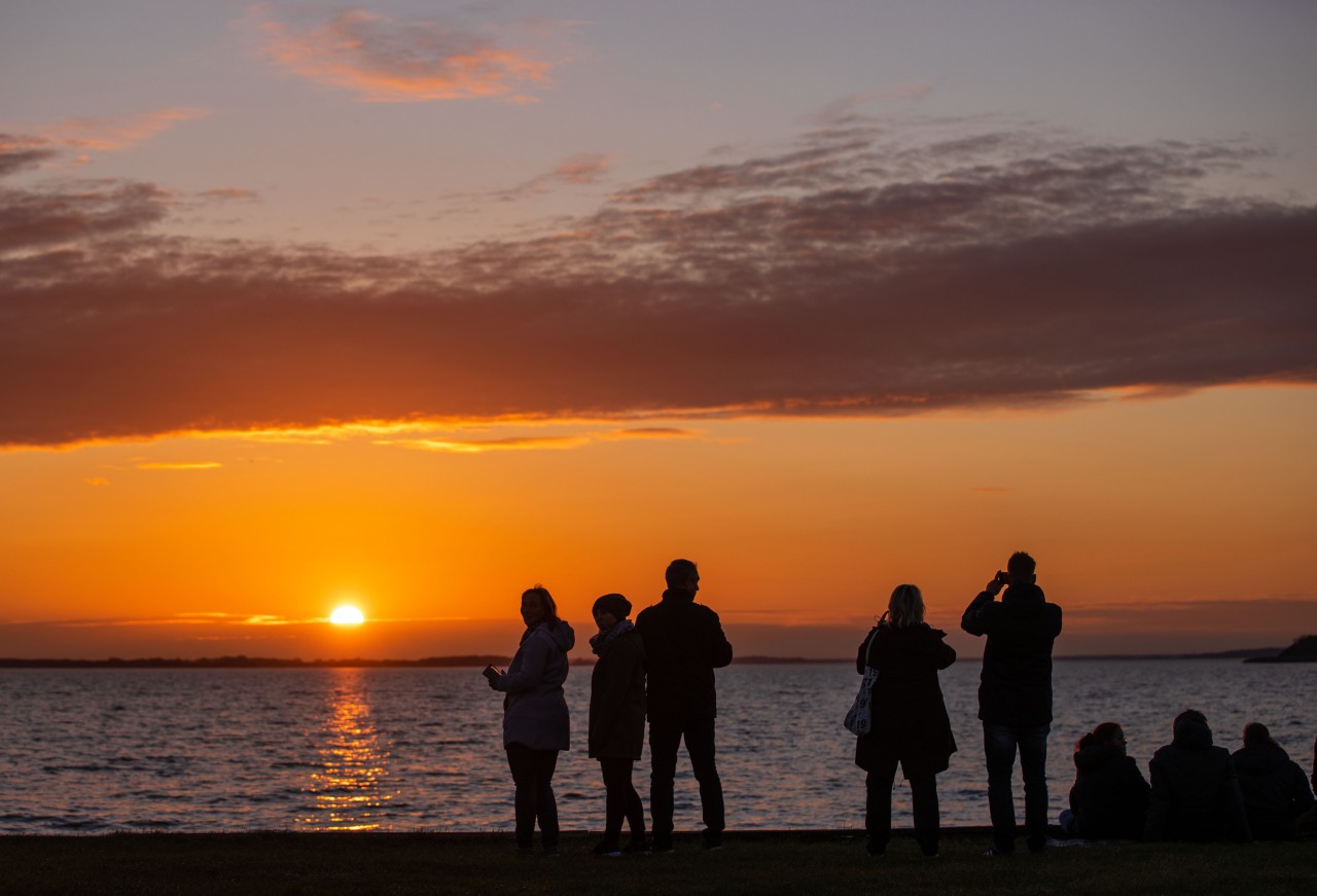 Strand-Besucher beobachten den Sonnenuntergang auf der Insel.