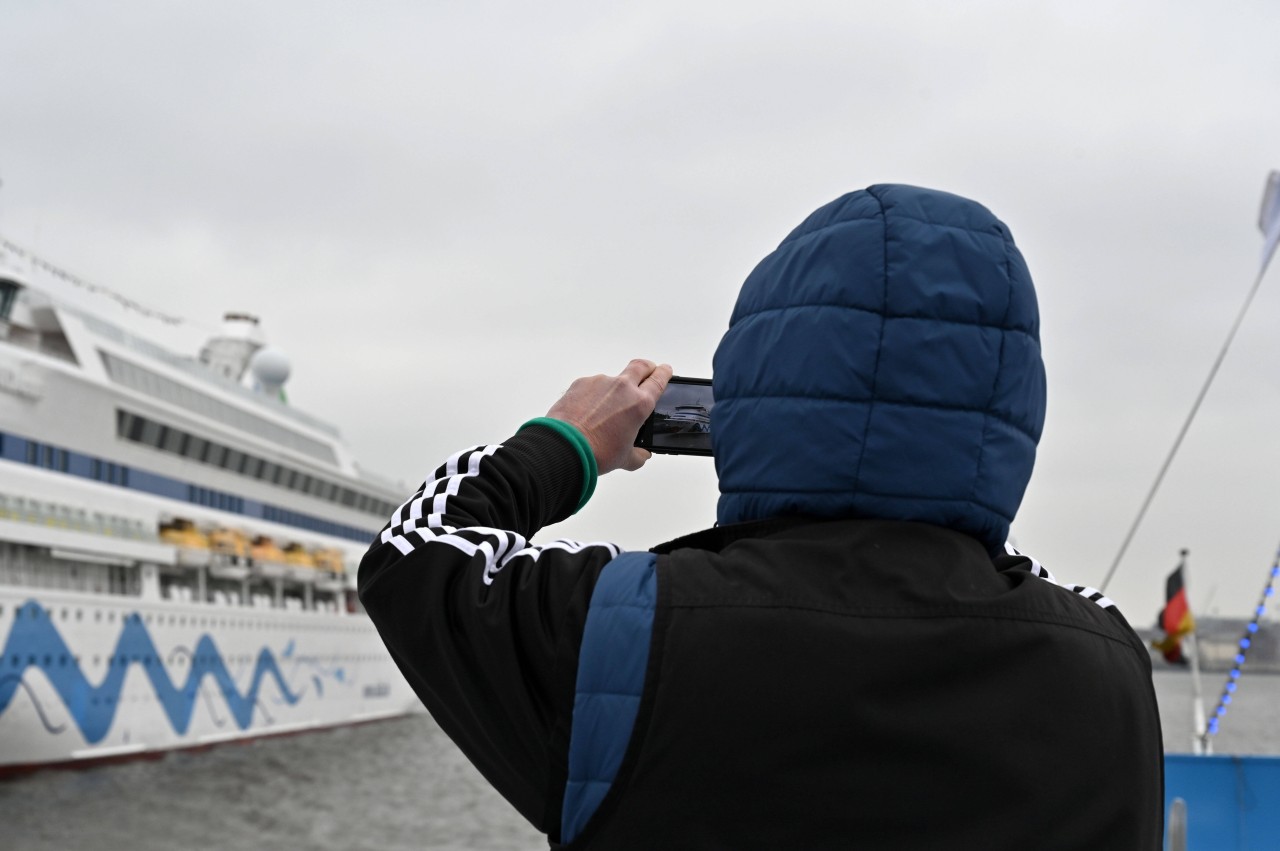 Ein Tourist fotografiert die „Aida Aura“ im Hafen von Hamburg vor der Corona-Pandemie.