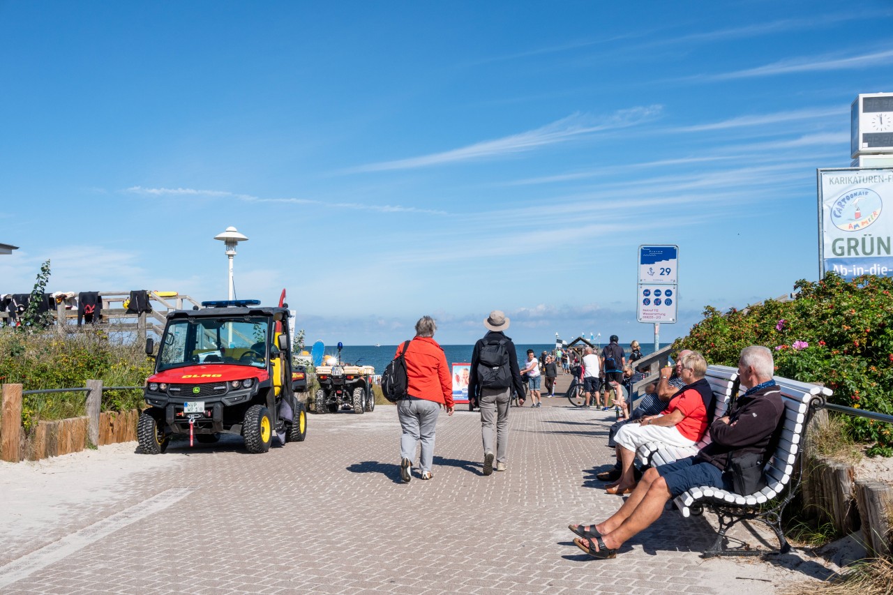 Touristen an der Ostsee. Links ein Fahrzeug der DLRG.