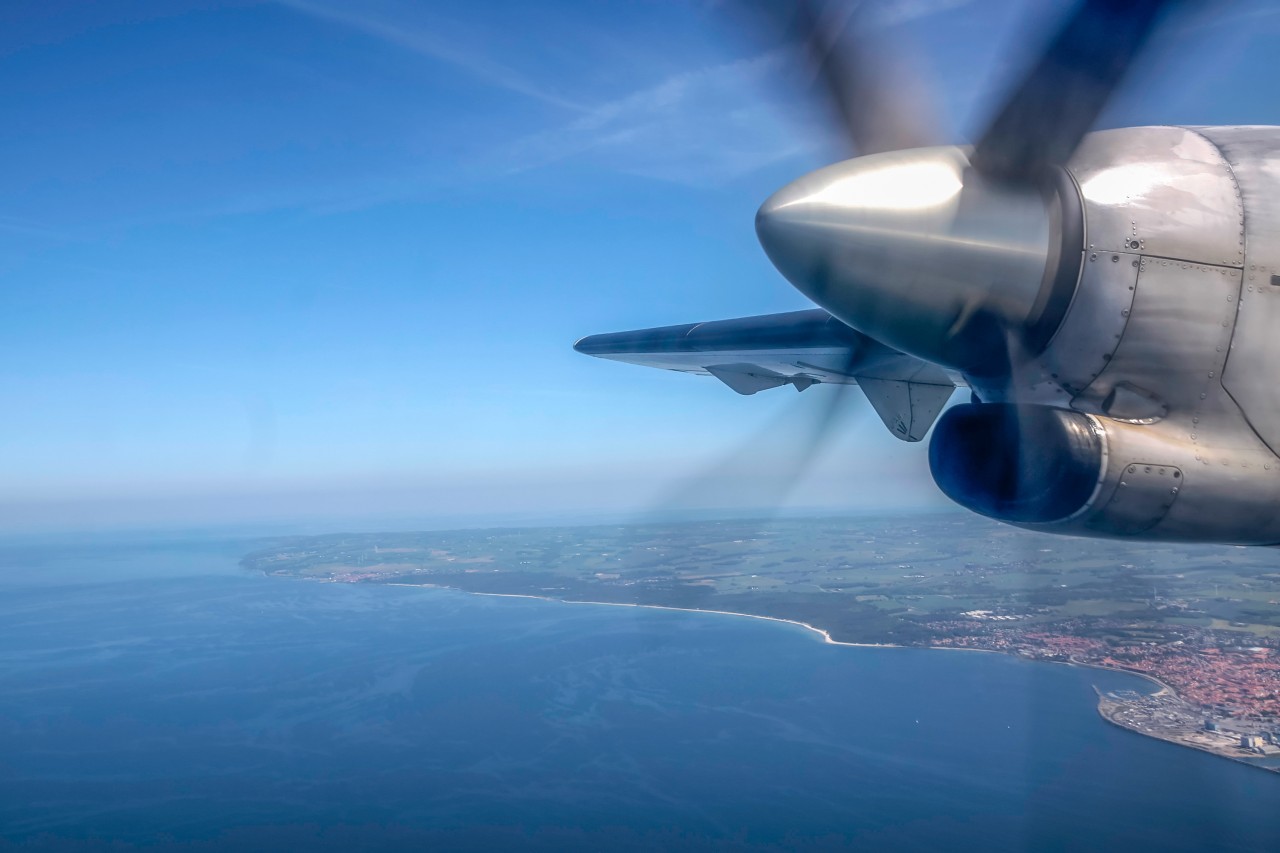Eine Propellermaschine fliegt über die Ostsee.