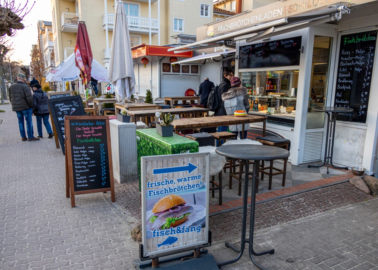 Die ersten Urlauber betrachten das Angebot einer geöffneten Imbissbude in Binz auf Rügen. 