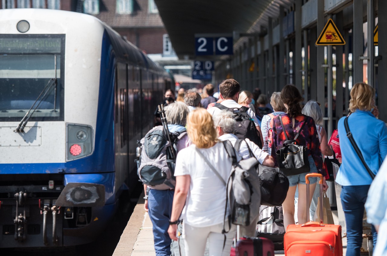 Sylt: Reisende gehen auf der Nordseeinsel im Bahnhof Westerland an einem Zug der Deutschen Bahn entlang. 
