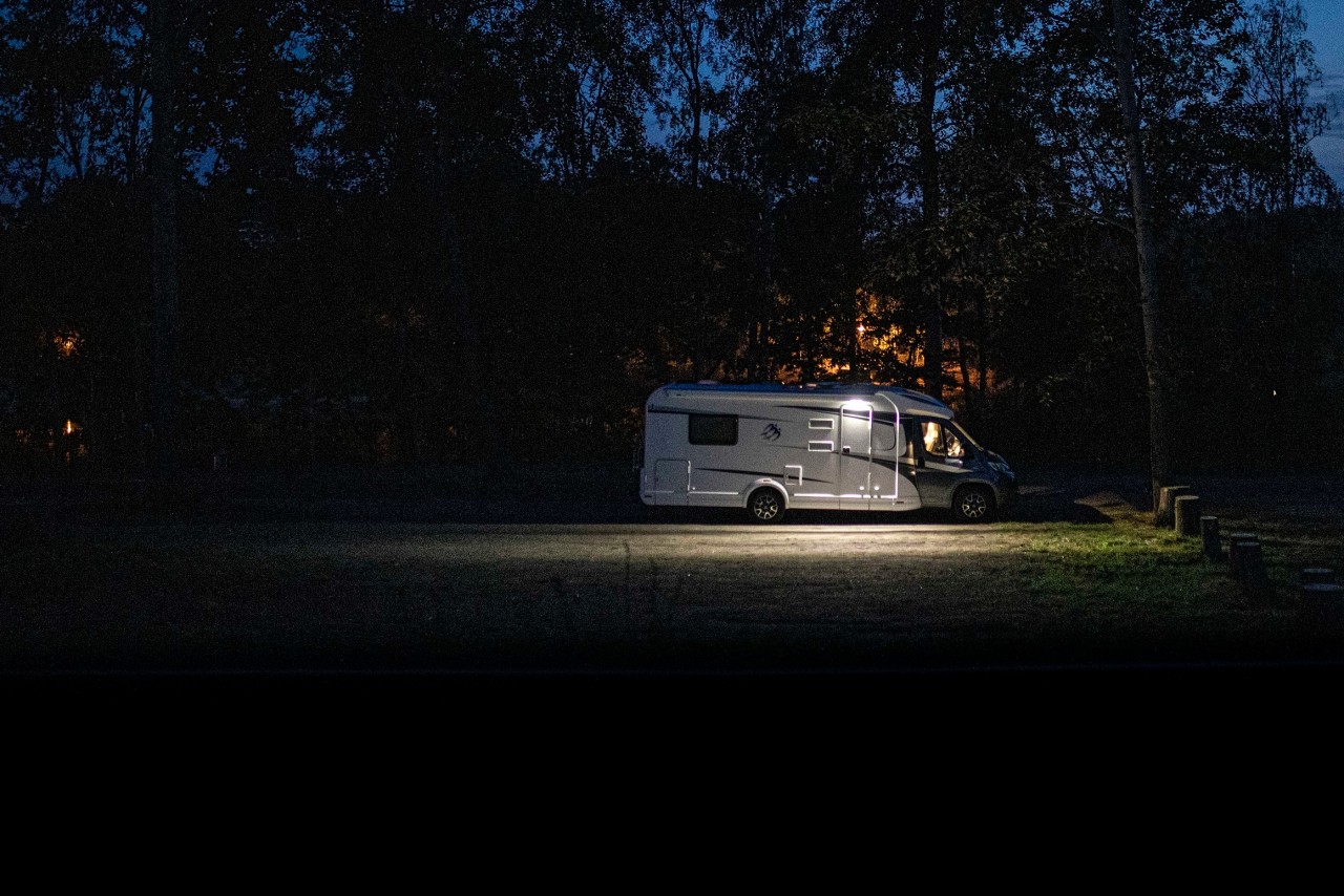 Camping: Ein beleuchtetes Wohnmobil steht an einem Straßenrand. (Symbolbild)