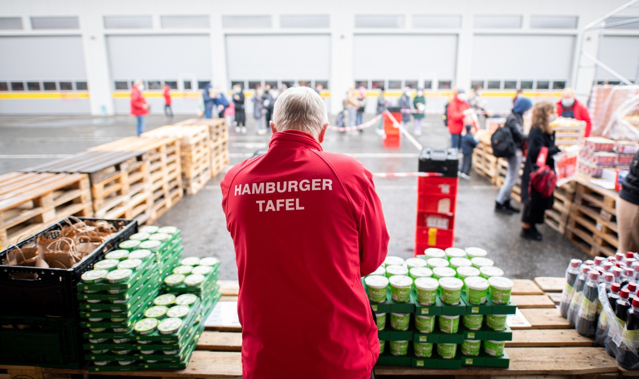 Ein Mitarbeiter der Tafel verteilt Lebensmittel an bedürftige Menschen in Hamburg.