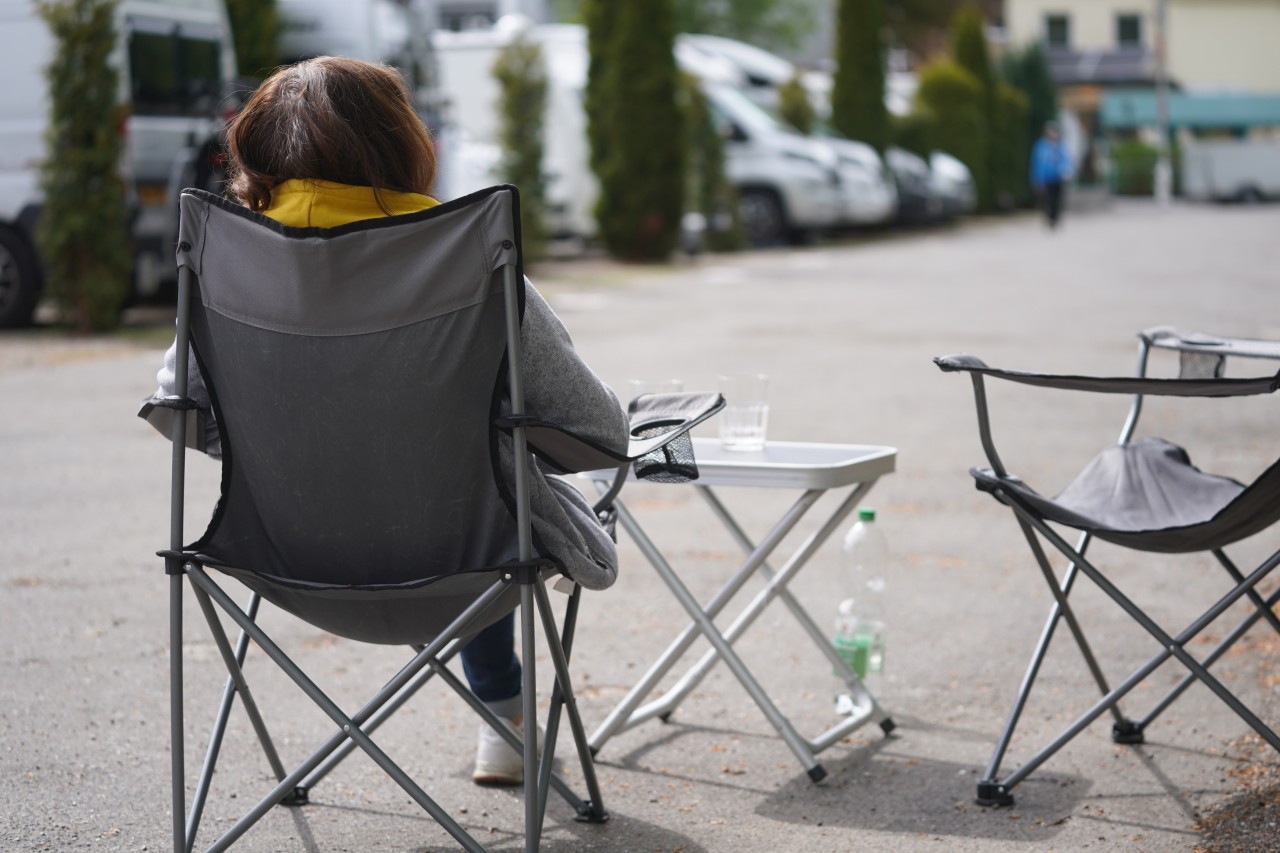 Eine Camperin sitzt in ihrem Stuhl auf dem Camping-Platz.
