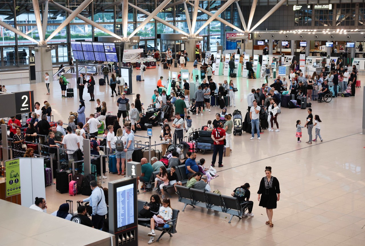 Flugreisende stehen vor den Check-In-Schaltern am Flughafen Hamburg. 