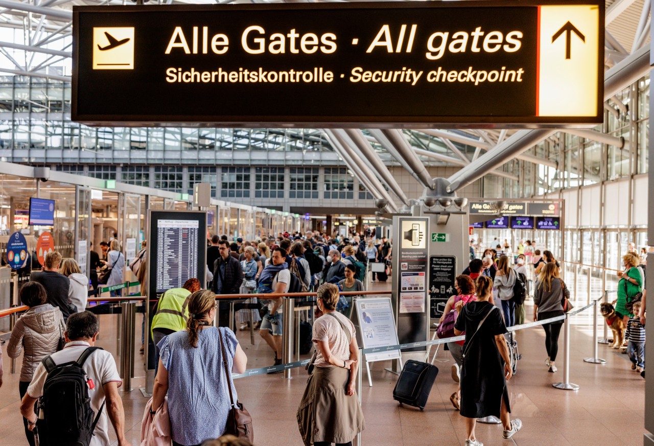 Fluggäste warten am Flughafen Hamburg vor dem Sicherheitscheck auf die Abfertigung.