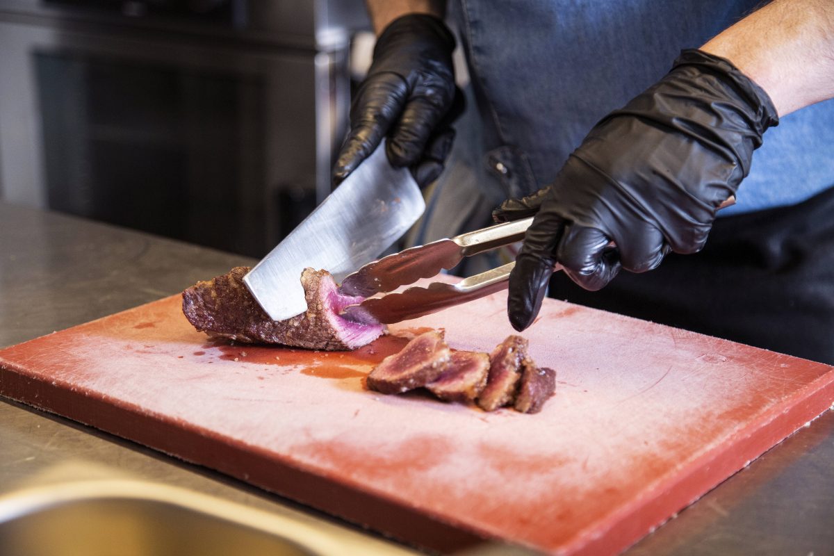 Ein Koch schneidet ein Steak in Scheiben.