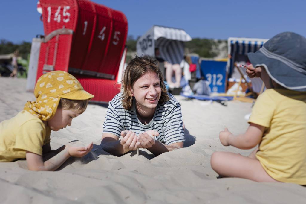Mann spielt mit Kindern im Sand