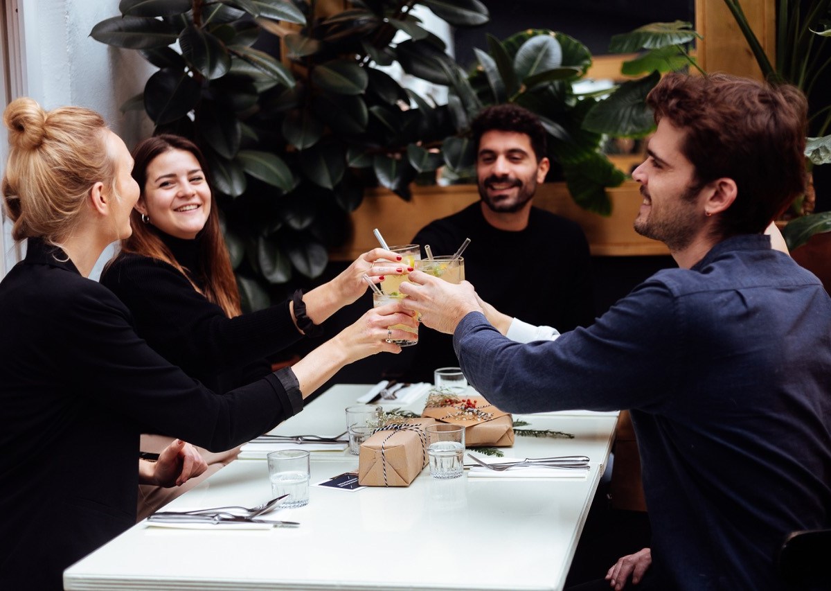 Freunde sitzen am Esstisch und stoßen an