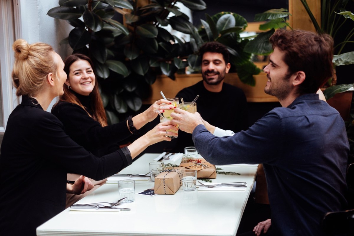Freunde sitzen am Esstisch und stoßen an