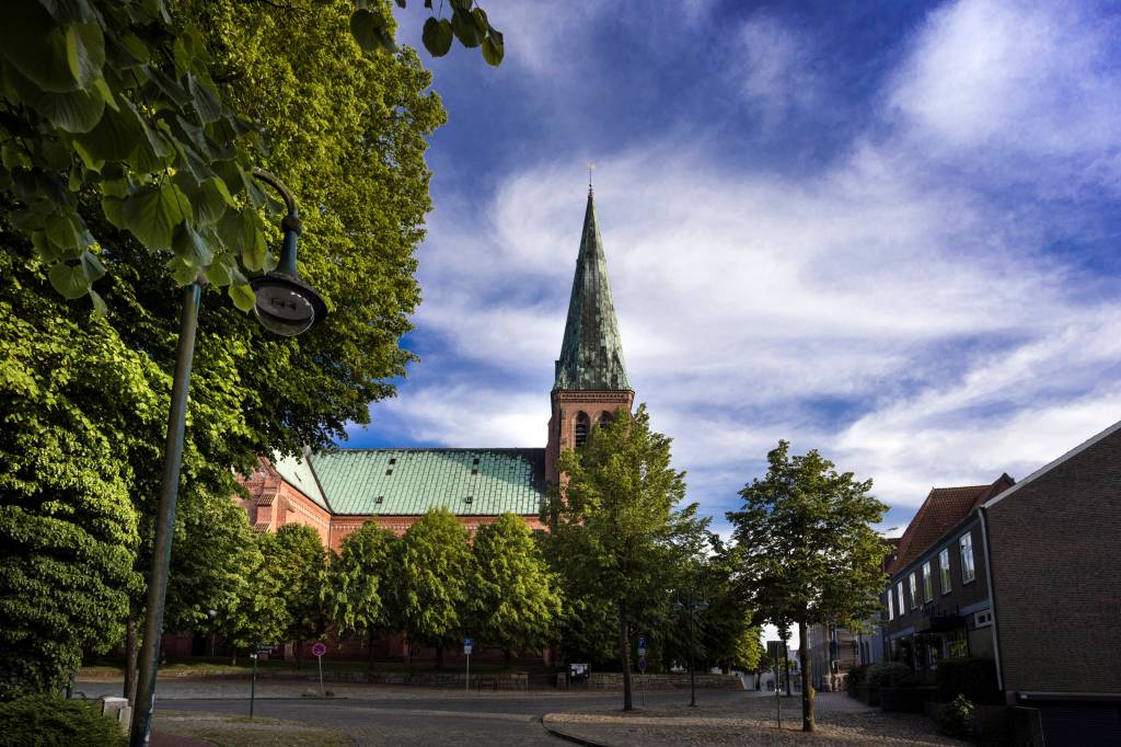 Kirche hinter Bäumen unter blauem Himmel