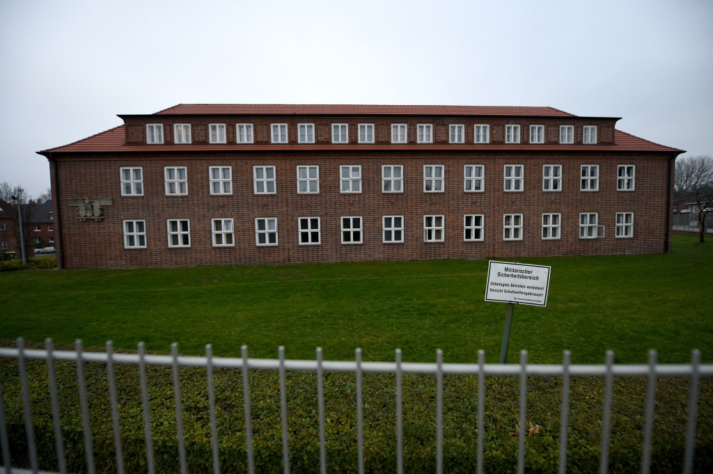 Rotes Backsteingebäude hinter Zaun auf grüner Wiese